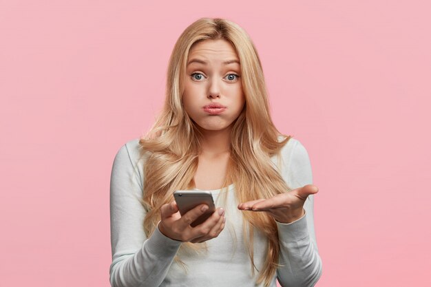 Beautiful blonde woman with white shirt holding phone