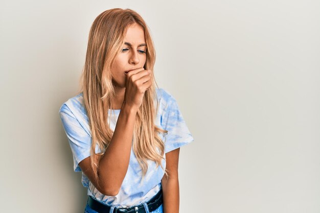 Beautiful blonde young woman wearing tye die tshirt feeling unwell and coughing as symptom for cold or bronchitis health care concept