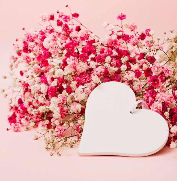 Beautiful bouquet of baby's-breath flowers with white heart shape on pink background