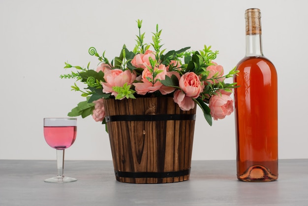 Free photo beautiful bouquet of flowers and bottle of rose wine on grey table.