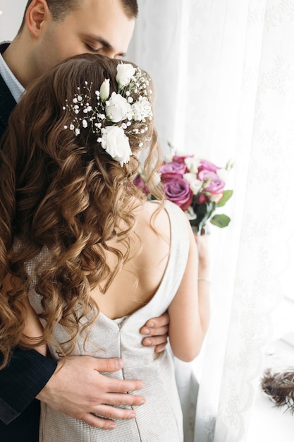 The beautiful bride and groom embracing in the room