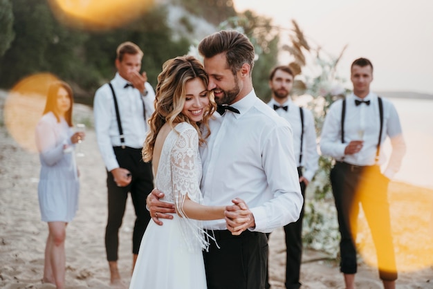 Free photo beautiful bride and groom having their wedding with guests on a beach