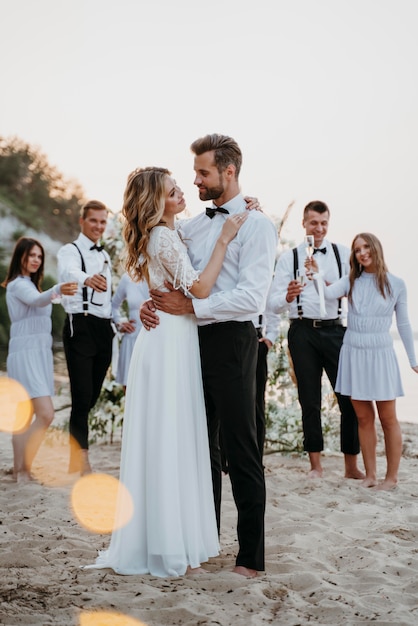 Beautiful bride and groom having their wedding with guests on a beach