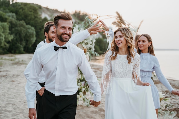 Free photo beautiful bride and groom having their wedding with guests on a beach