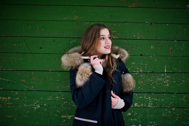 Free Photo beautiful brunette girl in winter warm clothing model on winter jacket against green wooden background