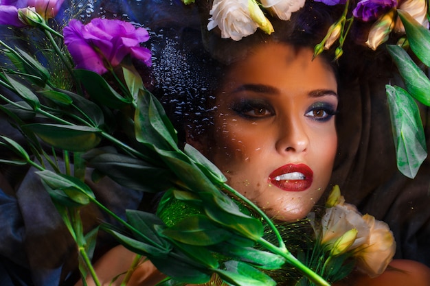 Free photo beautiful brunette girl with bright make up lying among eustomas.