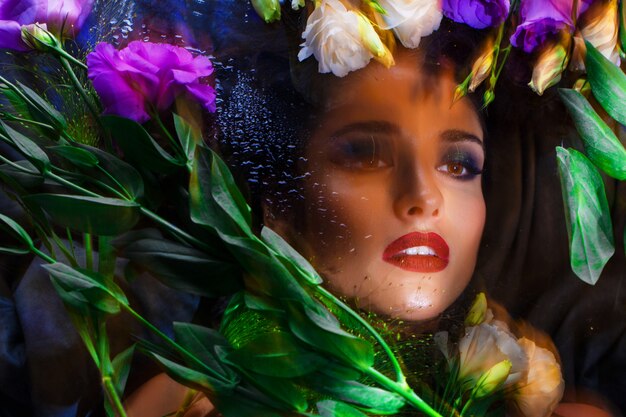 Beautiful brunette girl with bright make up lying among eustomas.