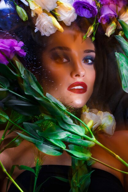 Beautiful brunette girl with bright make up lying among eustomas.