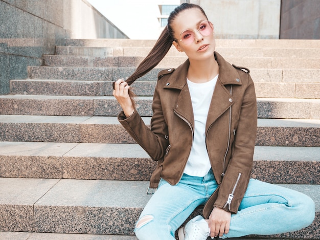 Free Photo beautiful brunette model dressed in summer hipster jacket and jeans clothes    playing with hair