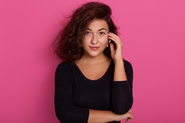 beautiful brunette woman with perfect skin posing isolated over pink, wearing black shirt