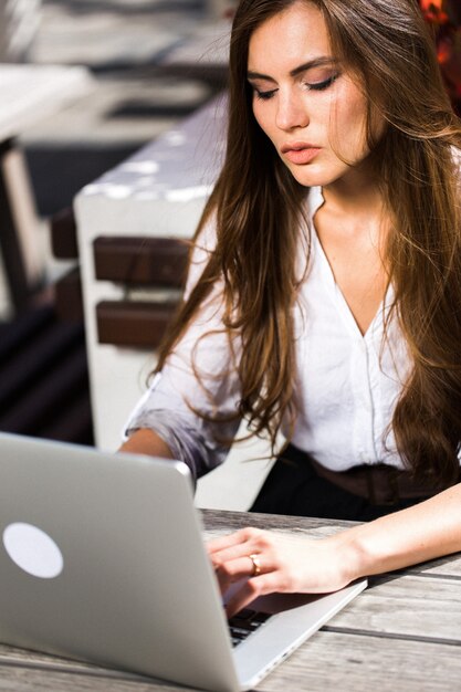 Beautiful brunette works with laptop outside