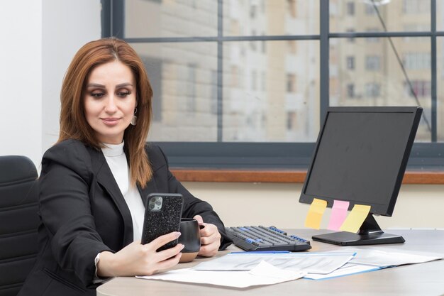 Beautiful business lady sitting at the office and taking selfie