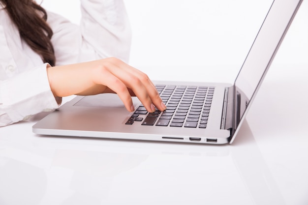 Beautiful business woman smile sitting at the desk working using laptop looking at screen, hand writing, isolated over white wall