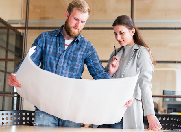 Free Photo beautiful businesswoman looking at blue print hold by her male colleague