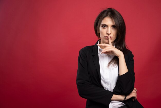 Beautiful businesswoman posing on red background. 