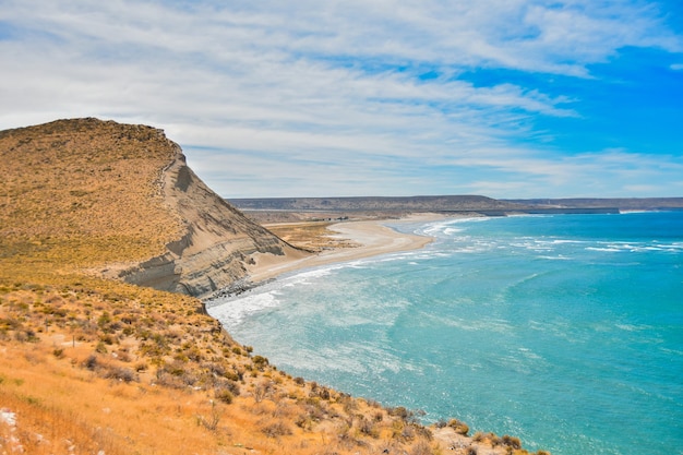 Free photo beautiful and calm ocean surrounded by the cliffs under the cloudy blue sky