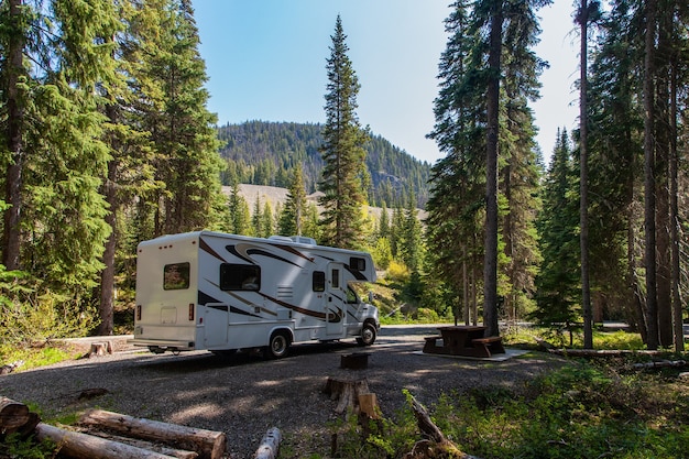 Beautiful campsite in the mountains with an RV and wooden bench.