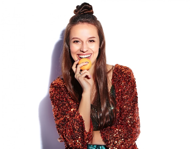 Beautiful caucasian smiling hipster brunette woman model in bright shinny reflecting summer stylish jacket and green dress isolated . Eating french macaroon