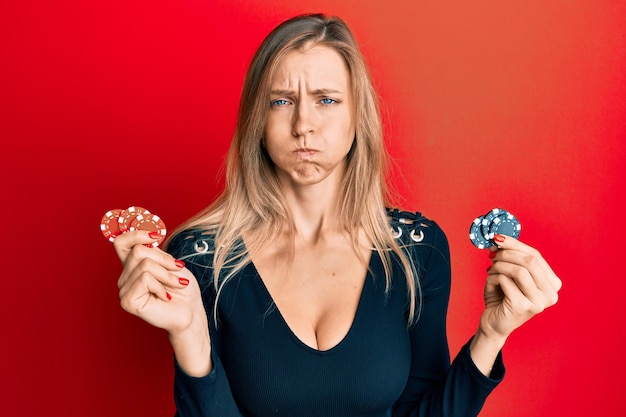 Free photo beautiful caucasian woman playing poker holding casino chips puffing cheeks with funny face mouth inflated with air catching air