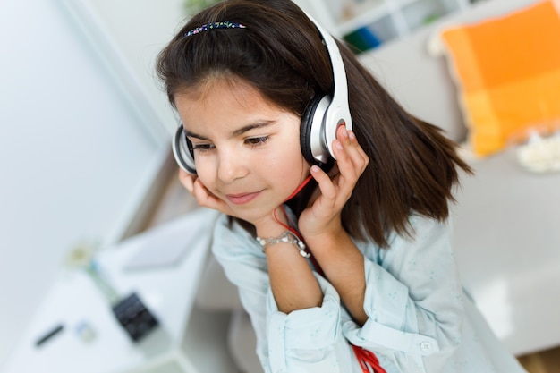 Beautiful child listening to music and dancing at home.