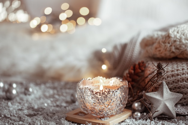 Beautiful Christmas candle in a candlestick on a light blurred background. The concept of home comfort and warmth.