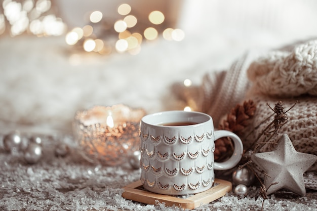 Free photo beautiful christmas cup with a hot drink on a light blurred wall. the concept of home comfort and warmth.