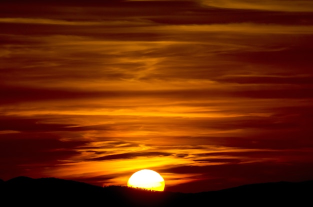 Free photo beautiful closeup shot of a sunset with read sky and half sun in tuscany, italy