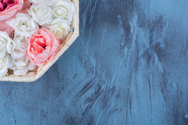 Free Photo beautiful colorful rose flower in wicker basket on blue.