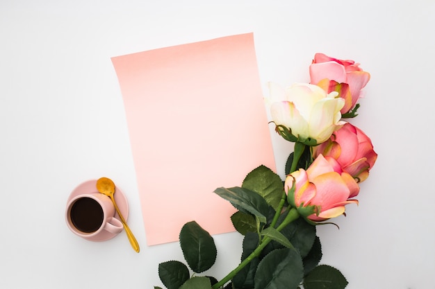 Beautiful composition with coffee, pink roses and blank paper on white 