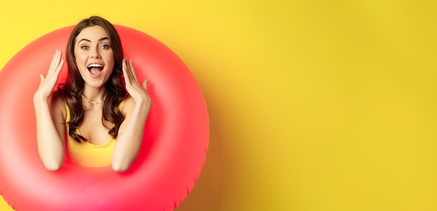 Free photo beautiful coquettish woman inside pink swimming ring posing on summer vacation beach holiday concept