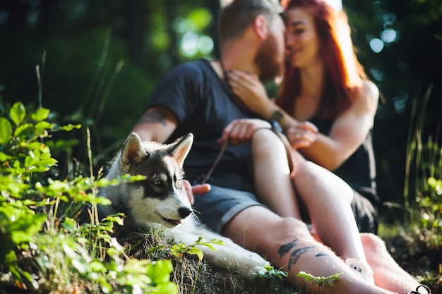 Beautiful couple and a dog have a rest in the forest