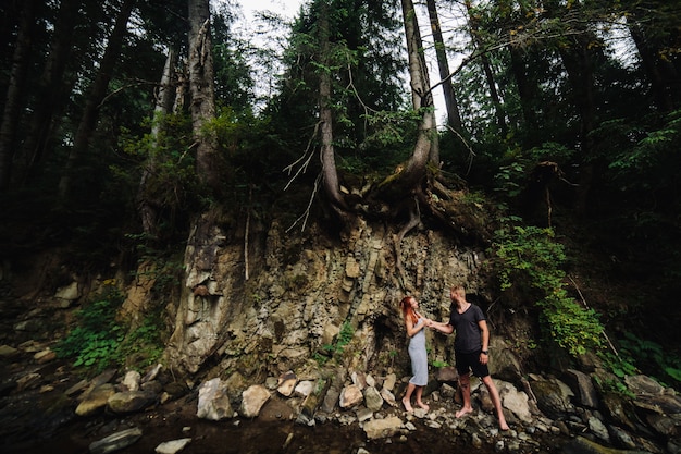 Beautiful couple hugging each other near a mountain river