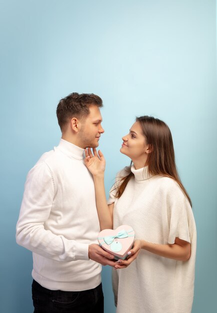 Beautiful couple in love on blue studio wall