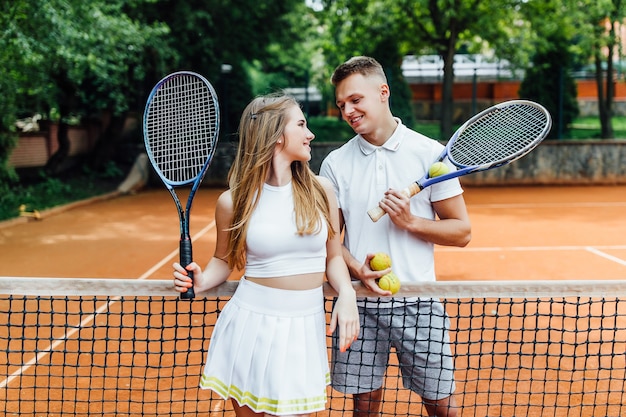 Beautiful couple playing tennis and looking happy to each other.