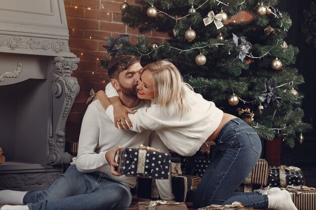 Beautiful couple sitting at home near christmas tree