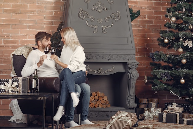 Free photo beautiful couple sitting at home near christmas tree