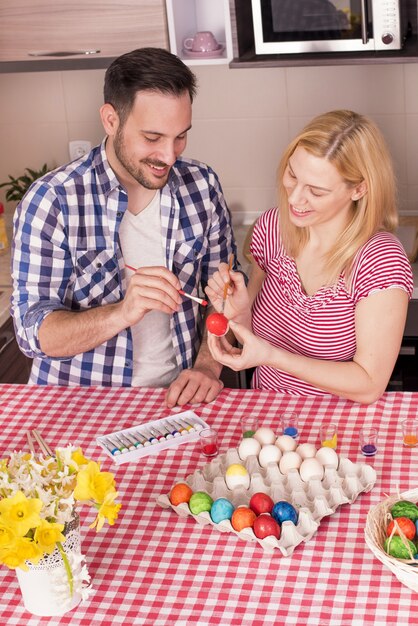 Free Photo beautiful couple smiling and painting the easter eggs