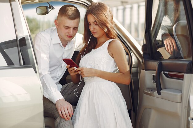 Beautiful couple spend time in a summer park near a car