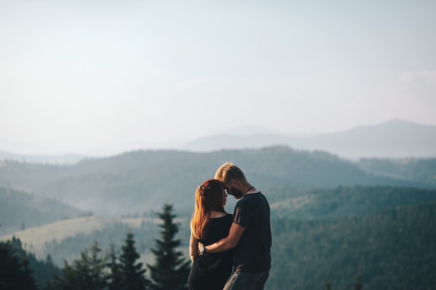 Free photo beautiful couple standing on a mountain and looking at each other