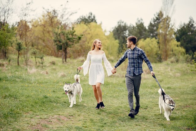 Beautiful couple in a summer forest with a dogs