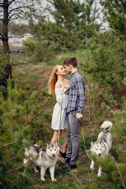 Beautiful couple in a summer forest with a dogs