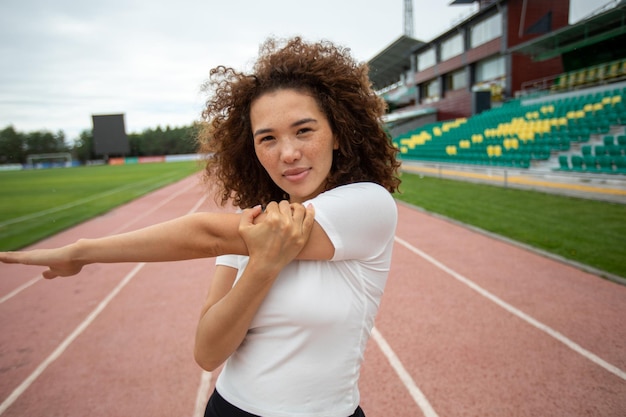 Beautiful curly girl warms up on the sports ground