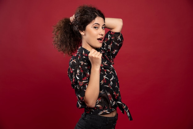 Beautiful curly woman holding her hair like ponytail.