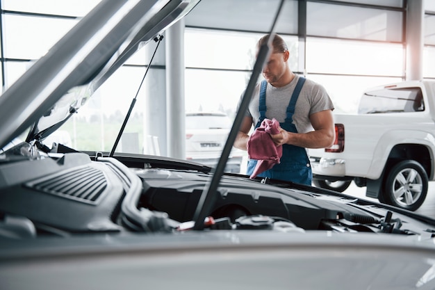 Free Photo beautiful day. man in blue uniform works with broken car. making repairings