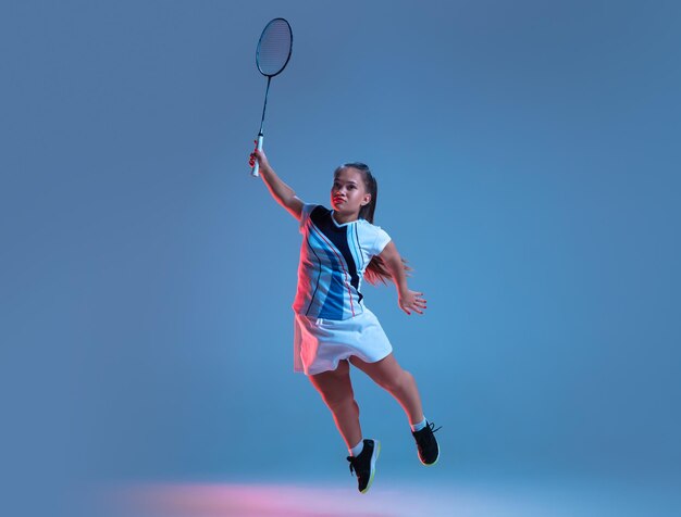 Beautiful dwarf woman practicing in badminton isolated on blue in neon light