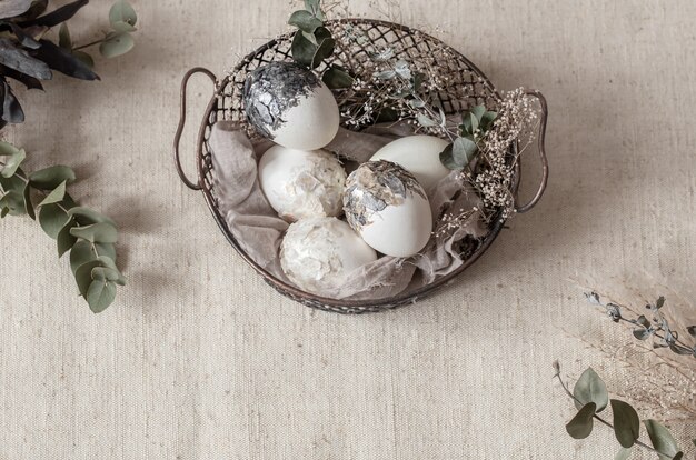 Beautiful Easter eggs in a basket decorated with dried flowers. Happy Easter concept.