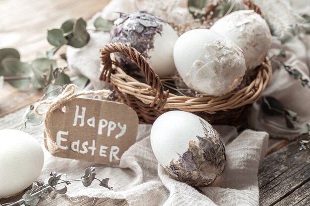 Beautiful Easter eggs in a basket decorated with dried flowers. Happy Easter concept.