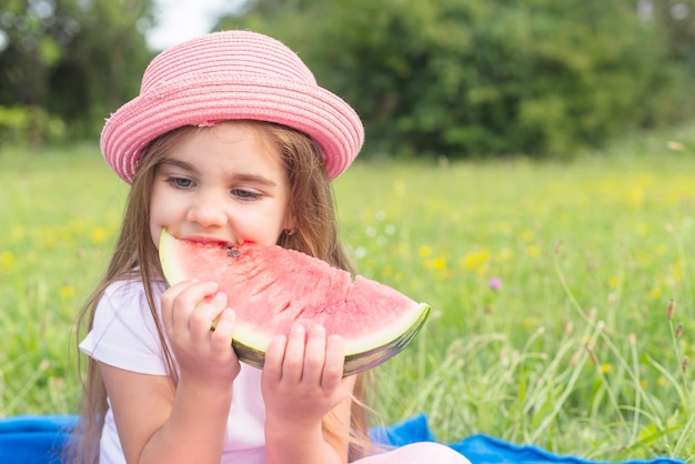 Beautiful eating watermelon slice sitting in the park