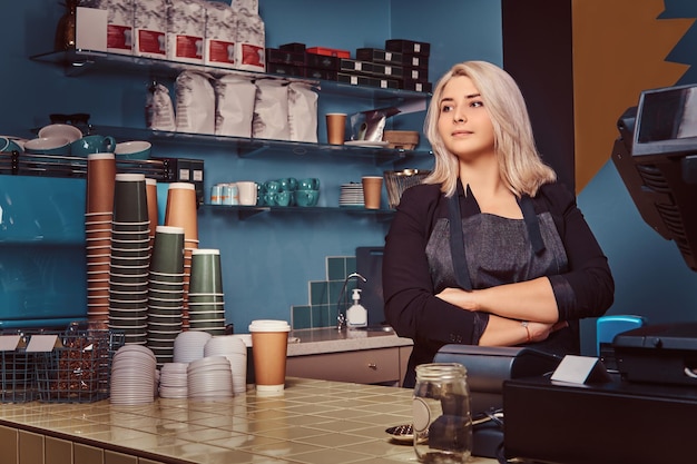 Free Photo beautiful experienced female barista in apron standing with crossed arms at the coffee shop.