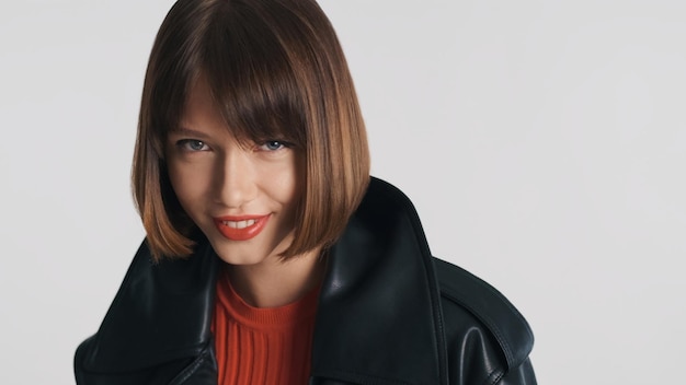 Free photo beautiful fashion model with bob hair and red lips confidently looking in camera and smiling over white background